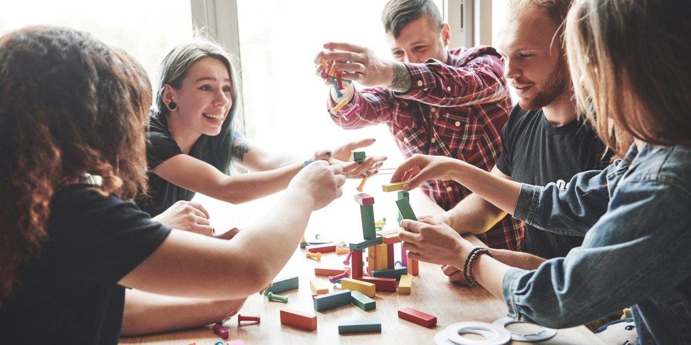 Optimized-group-creative-friends-sitting-wooden-table-people-were-having-fun-while-playing-board-game (1)
