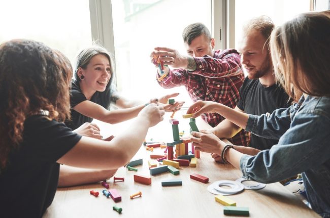 Optimized-group-creative-friends-sitting-wooden-table-people-were-having-fun-while-playing-board-game (1)